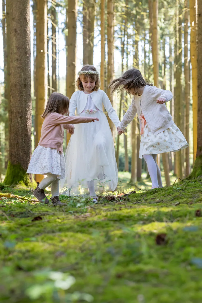 Kind in hellem Kleid in einem lichten Wald