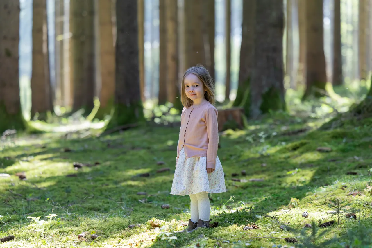 Mädchen in Rosa in einem sonnendurchfluteten Wald