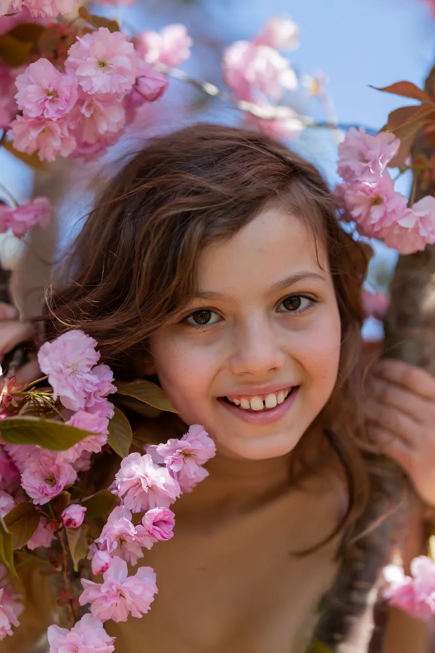 Mädchen lacht zwischen rosa Kirschblüten